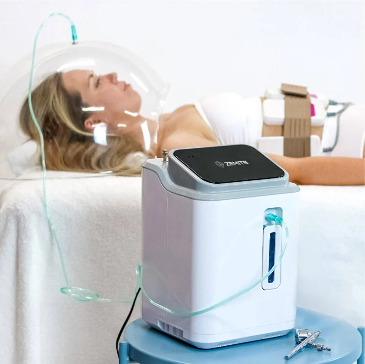 Client lying on a treatment bed with a transparent oxygen dome over the face connected to a Zemits oxygen infusion machine during a professional facial treatment.